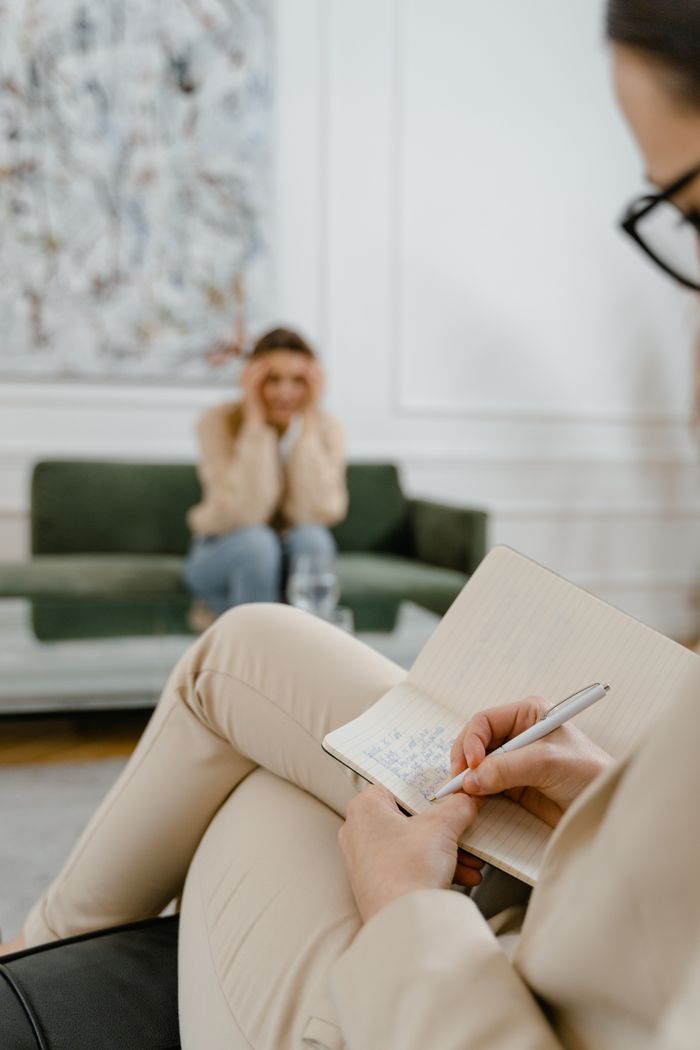 about-us-01 A therapist takes notes in a modern office setting during a therapy session with a patient.